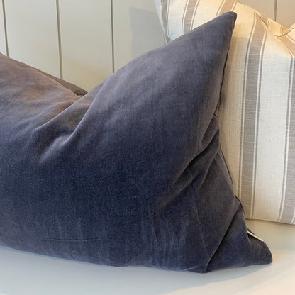 Gray pillow on a white surface with a striped pillow in the background